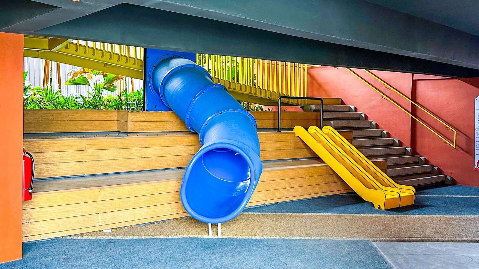 Área de juegos techada y colorida con toboganes azul y amarillo