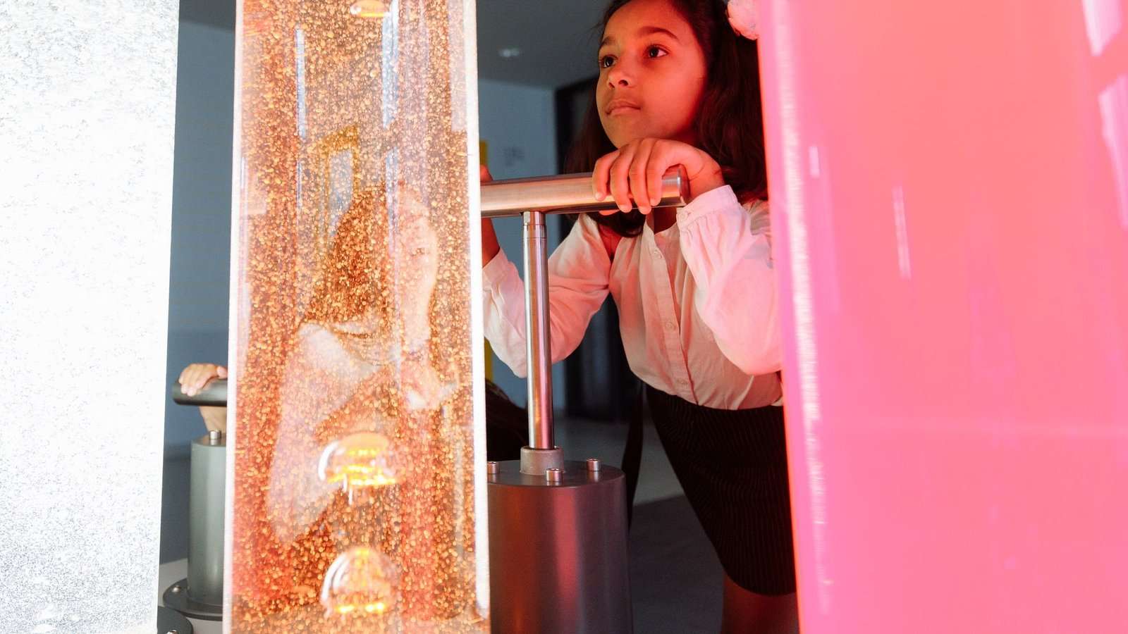 Niña mirando una columna de líquidos de colores en un museo de ciencias