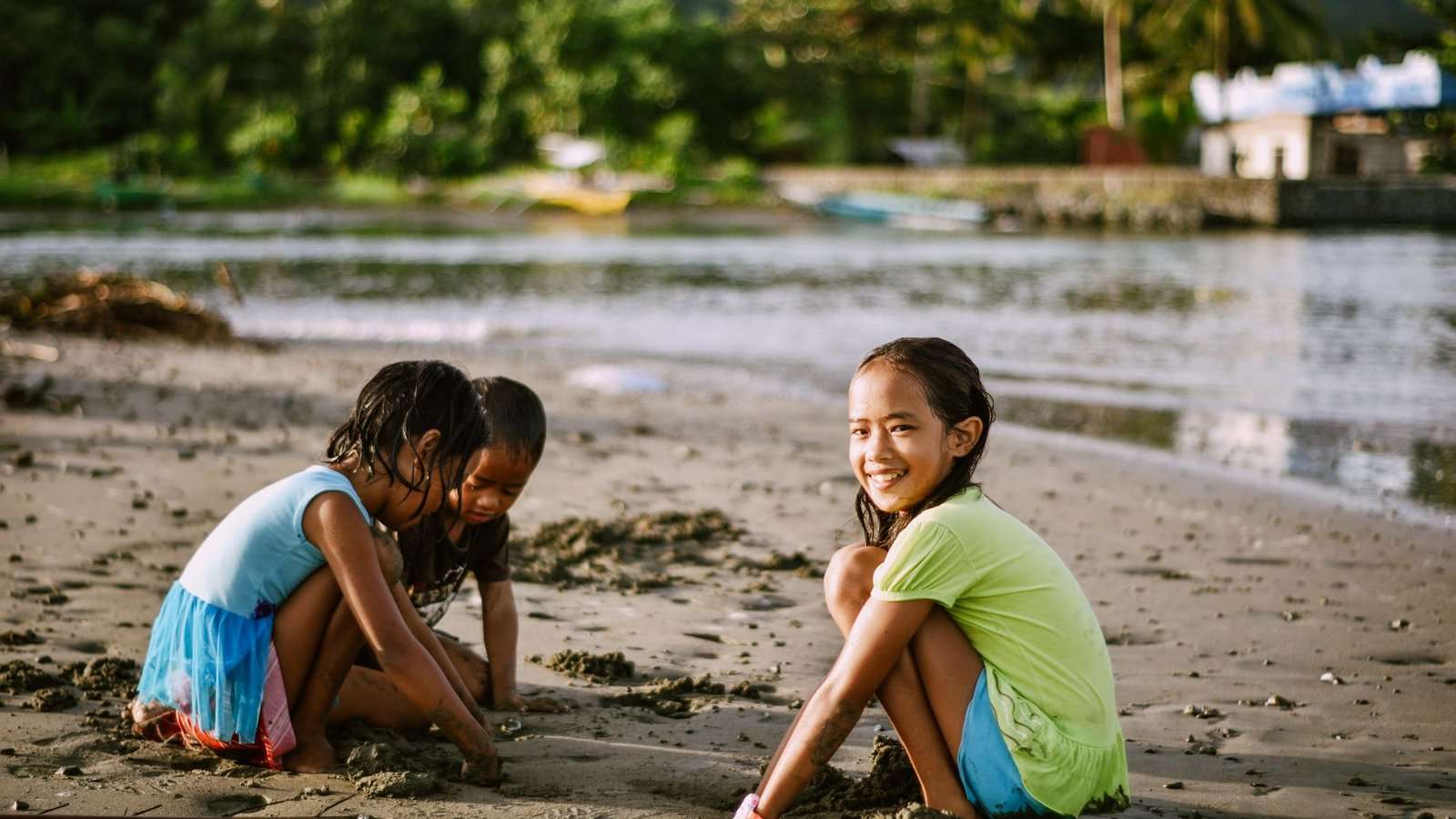 Dos niñas juegan con la arena mojada en la orilla de la playa